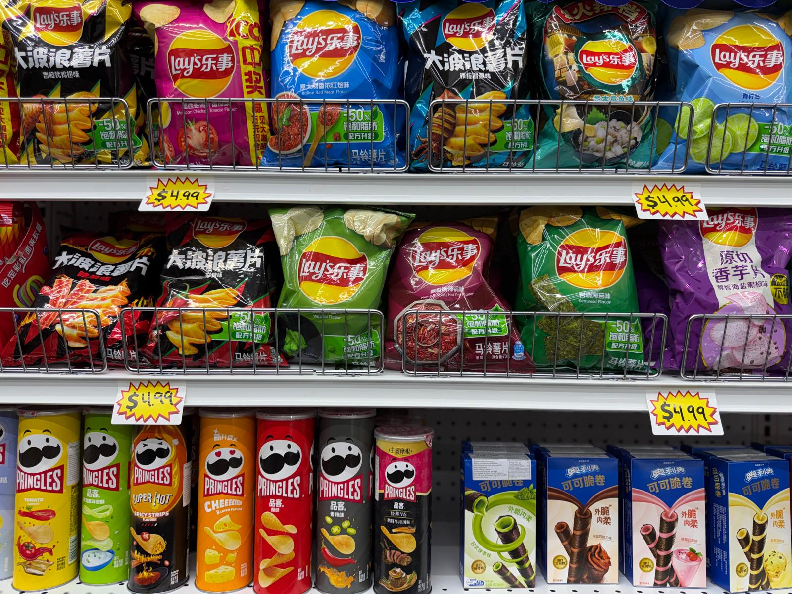 Imported Chinese Lay's chip flavors and international Pringles cans on shelves at One Stop Market N Smoke Shop in Hialeah, FL.