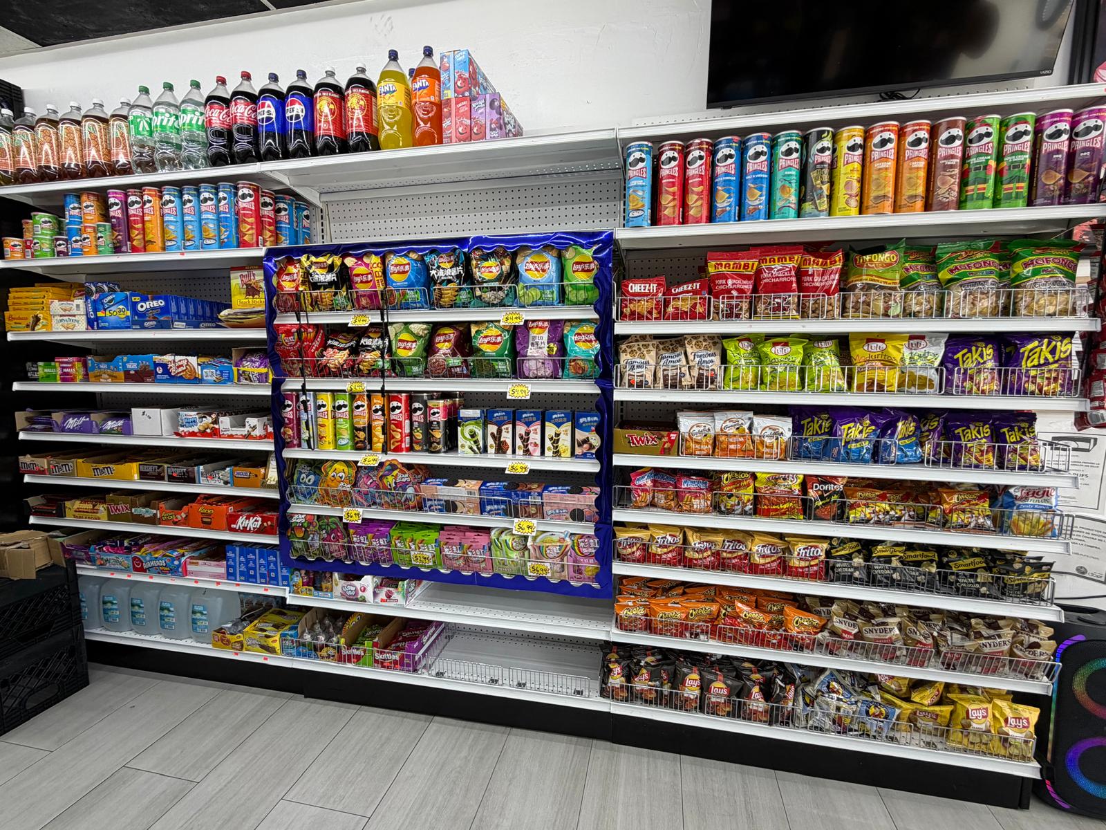 Snack and candy aisle at One Stop Market N Smoke Shop in Hialeah, FL with Takis, Cheetos, Pringles, Oreos, and sodas.